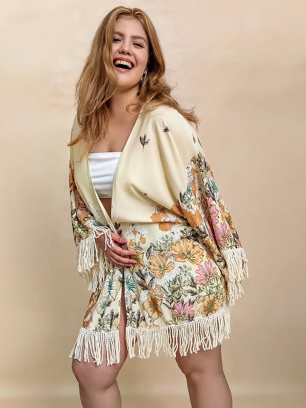 Woman wearing a floral sweater with fringe on a beige background