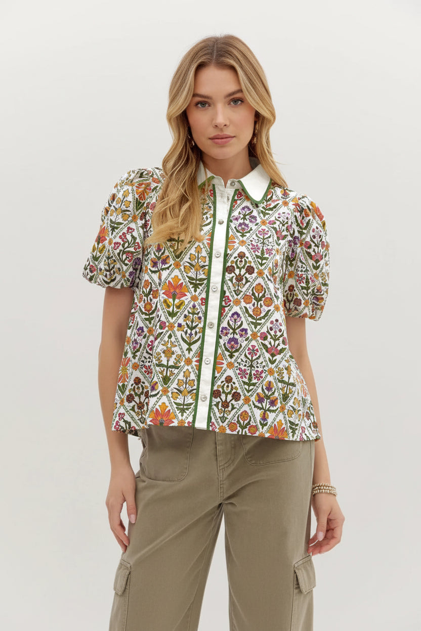 Person wearing a colorful floral patterned shirt with a plain background