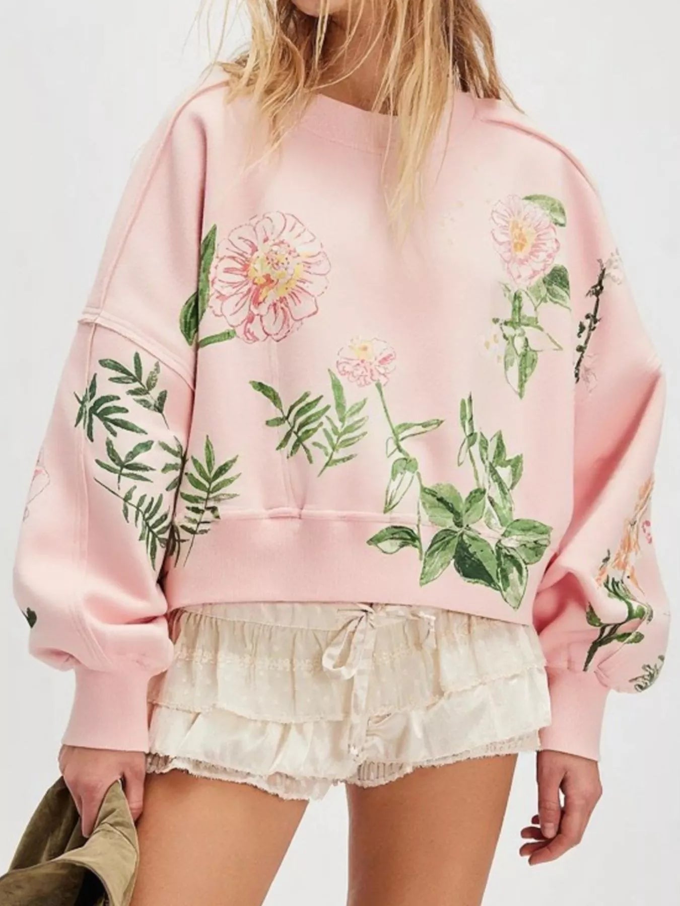Person wearing a pink sweatshirt with floral designs 