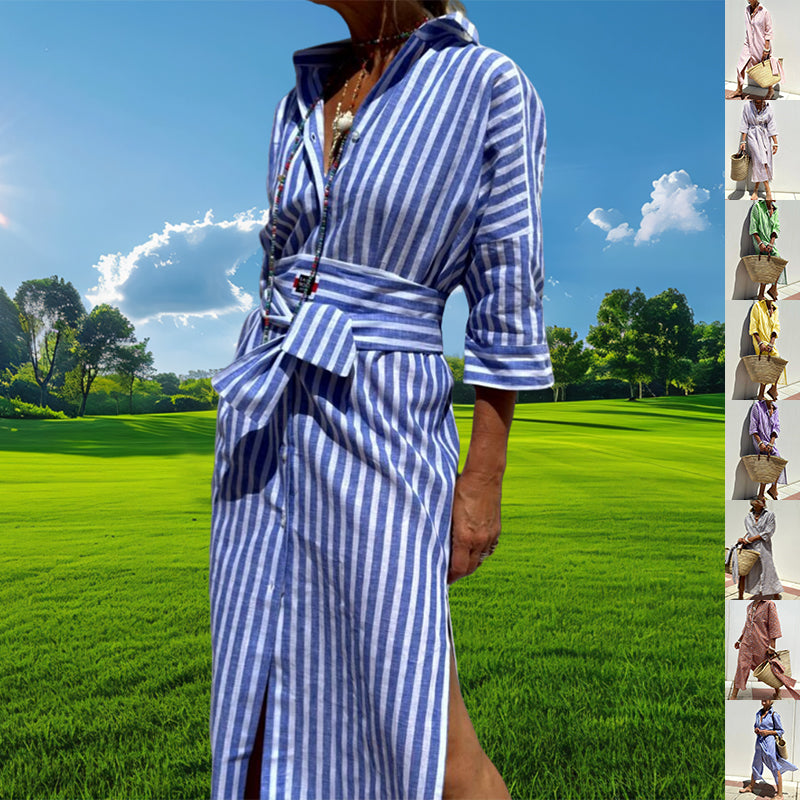 A woman outdoors in a blue and white vertically striped long dress or robe-style garment with a tie waist and rolled sleeves, set against a bright green field and blue sky. A narrow vertical strip on the right shows smaller alternate color variants of the garment.