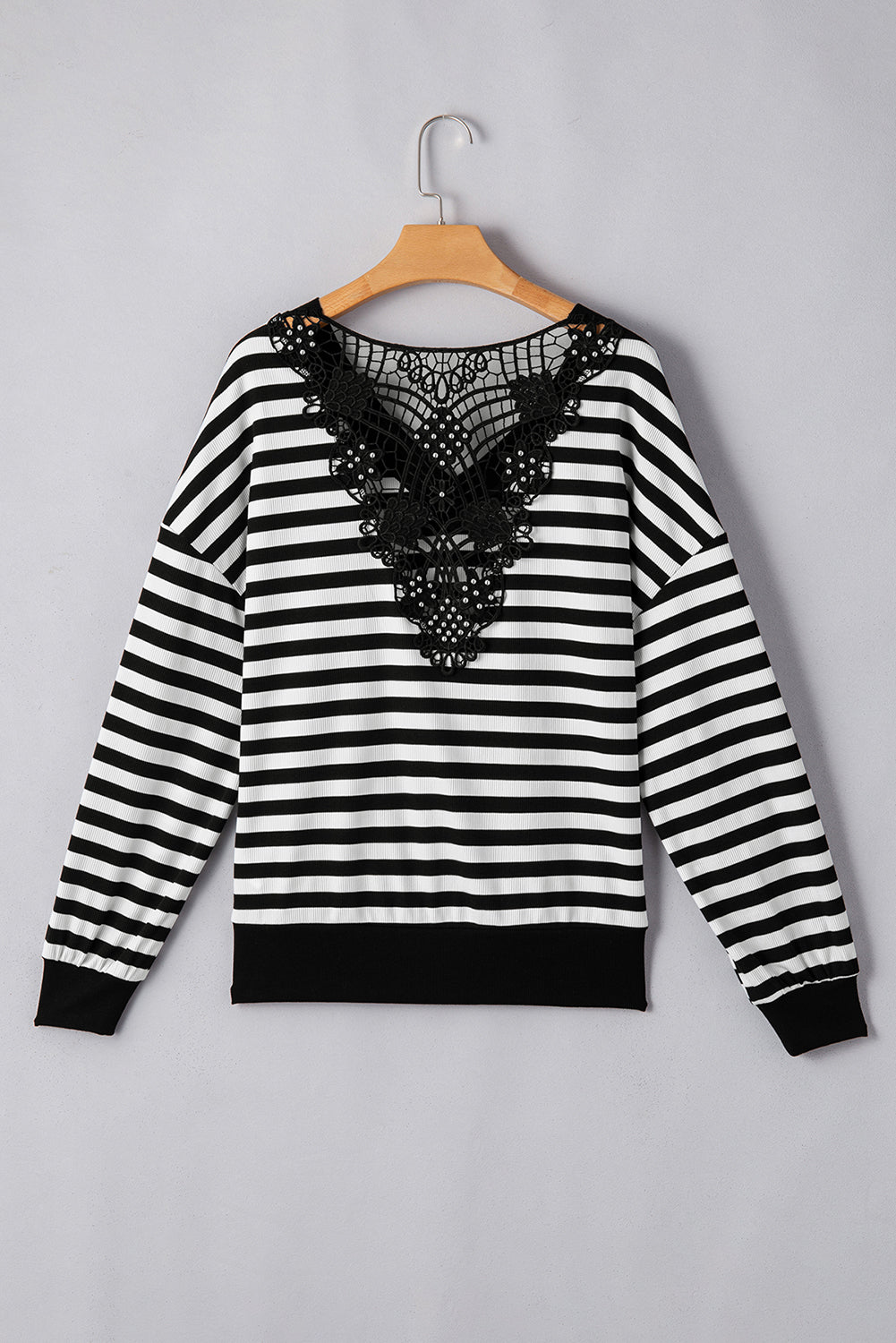 Black and white striped sweater with lace detail on a hanger 