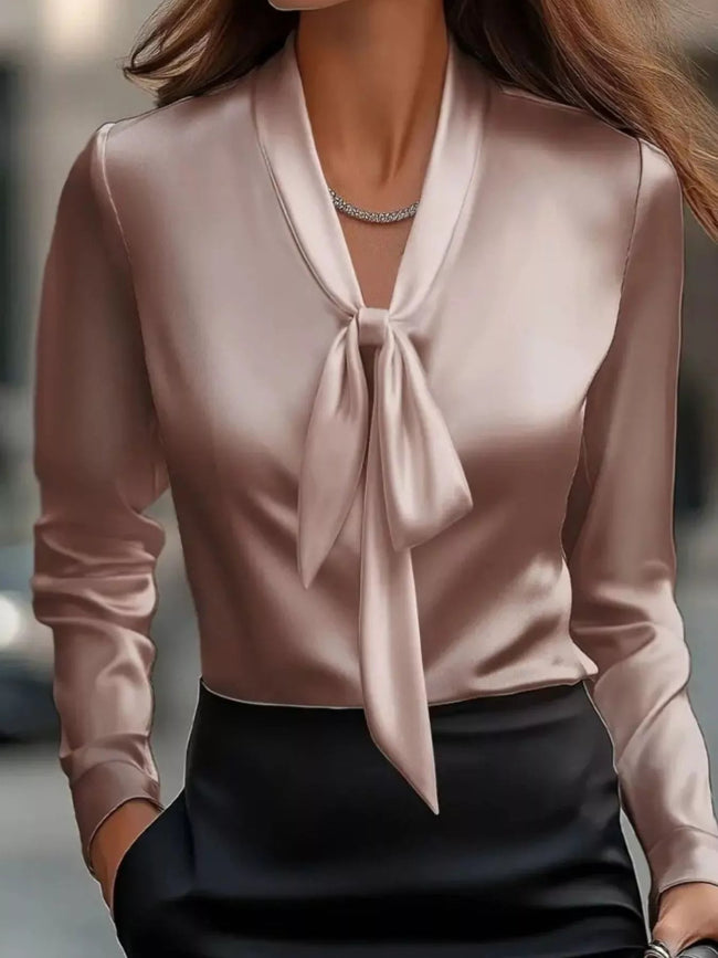 Close-up of a person wearing a light pink blouse with a tie detail 