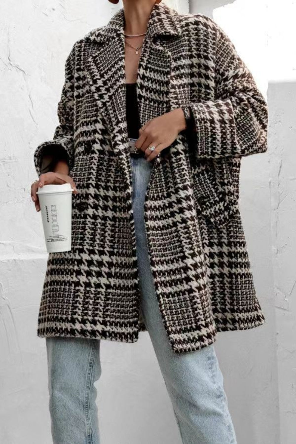 A woman wearing a houndstooth collared neck long sleeve coat with pockets