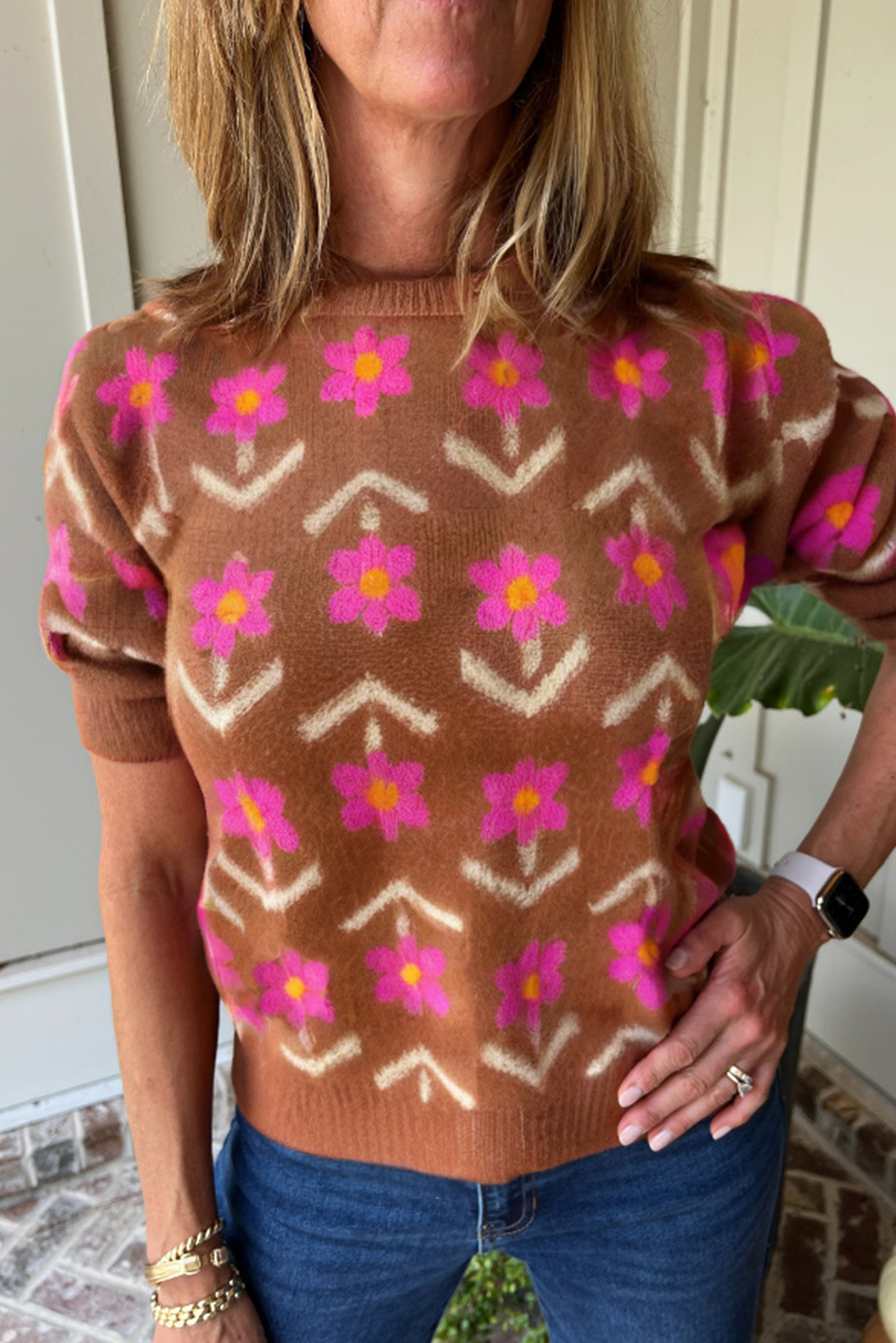 Person wearing a brown sweater with pink floral pattern 