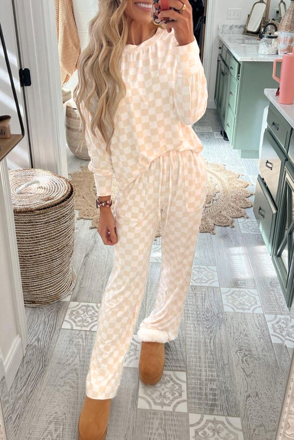 A woman wearing a beige checkered print long sleeve top and matching pants lounge set.