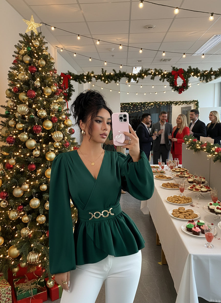 Woman taking a mirror selfie wearing a green peplum top and white pants.
