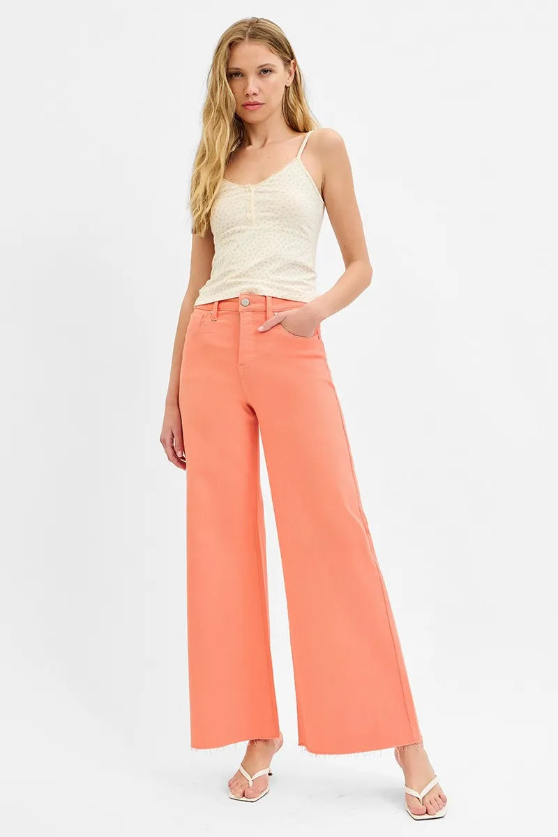 Woman wearing a white top and coral wide-leg pants on a white background