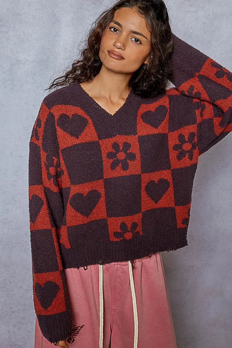 Woman wearing a red and burgundy checkered sweater with heart and flower print patterns 