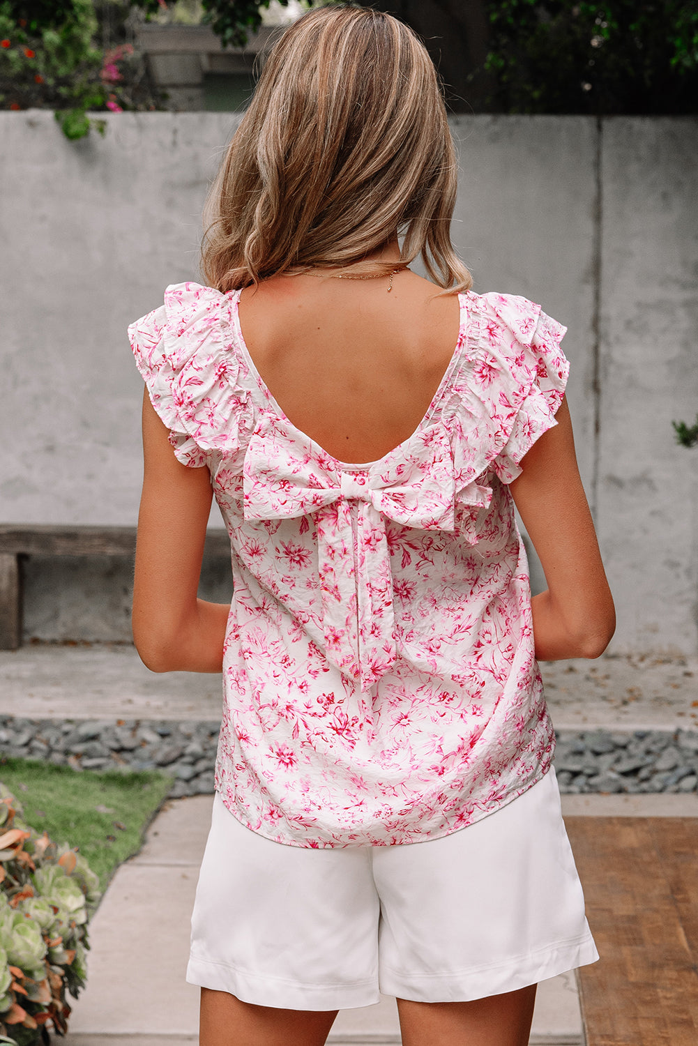 Person wearing a pink floral top with ruffled sleeves and a bow 