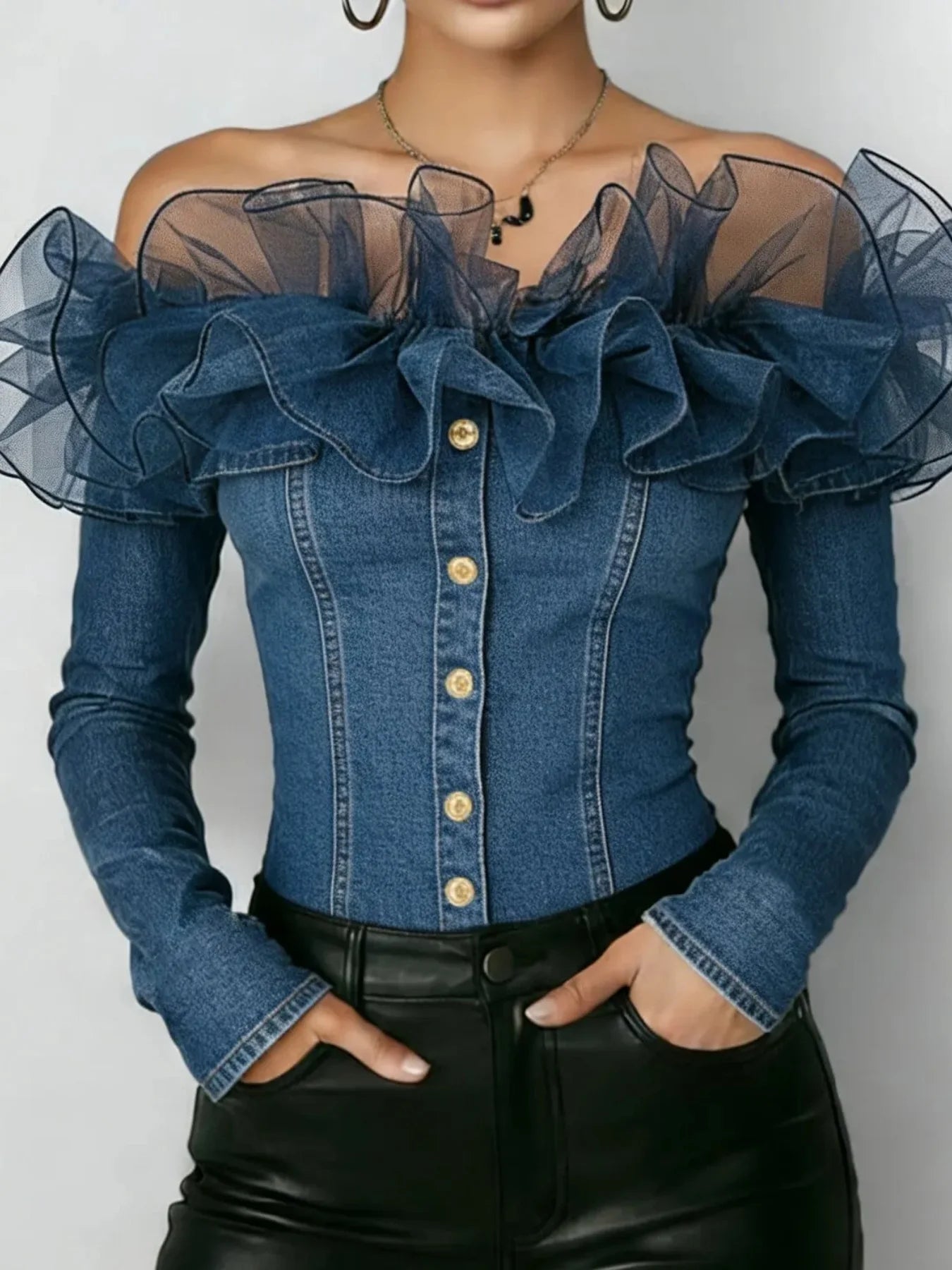 A woman wearing a blue denim off-the-shoulder top with sheer mesh ruffle sleeves, gold-tone buttons down the front, and black leather pants, shown from the neck to the hips against a plain light background.