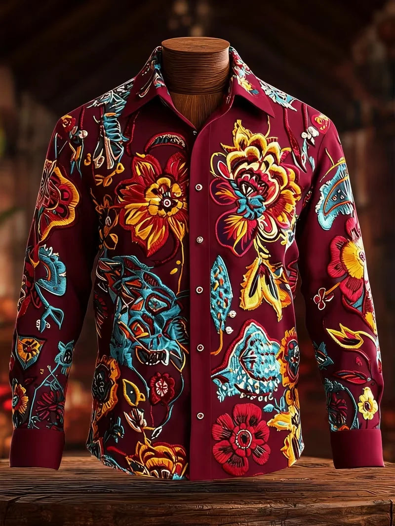 A long-sleeve button-up shirt displayed on a wooden mannequin torso, featuring a rich burgundy base with vibrant, hand-painted style floral and folk-art motifs in yellow, red, blue, and orange.