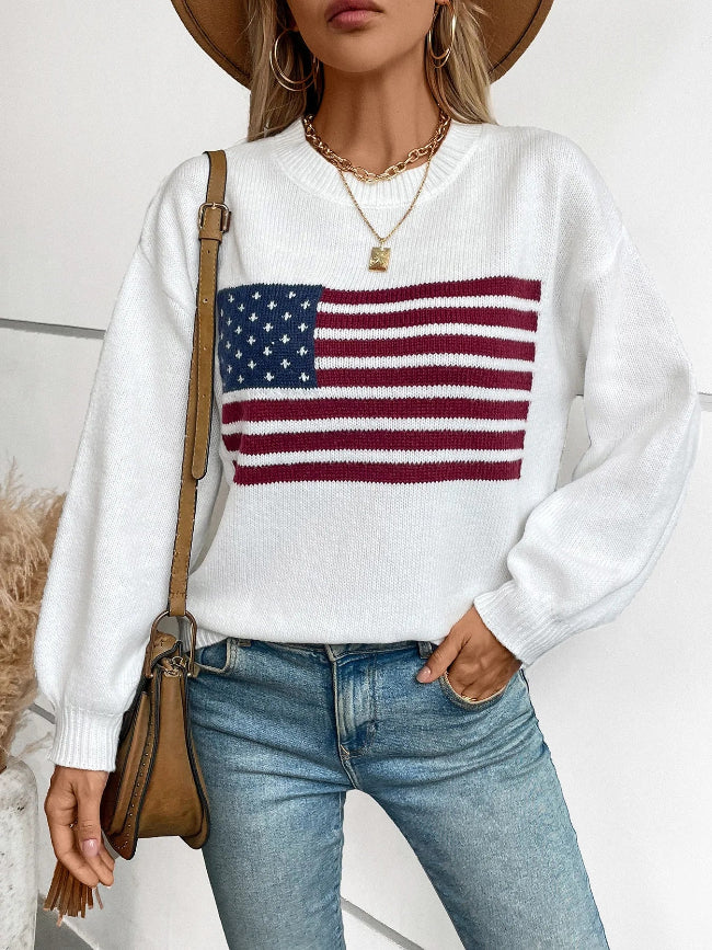 Person wearing a white sweater with an American flag design, blue jeans, and a brown bag.