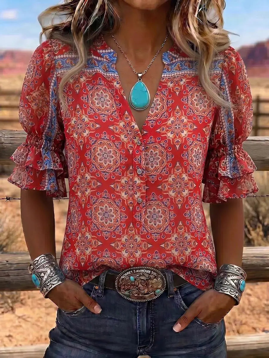 Person wearing a red patterned blouse with ruffled sleeves, turquoise jewelry, and a belt buckle.