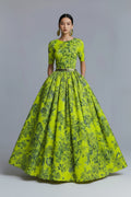 Woman wearing a bright green floral dress against a gray background