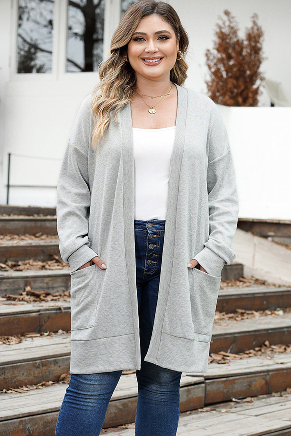 A woman wearing a gray thermal knit cardigan with an open front design and long sleeves