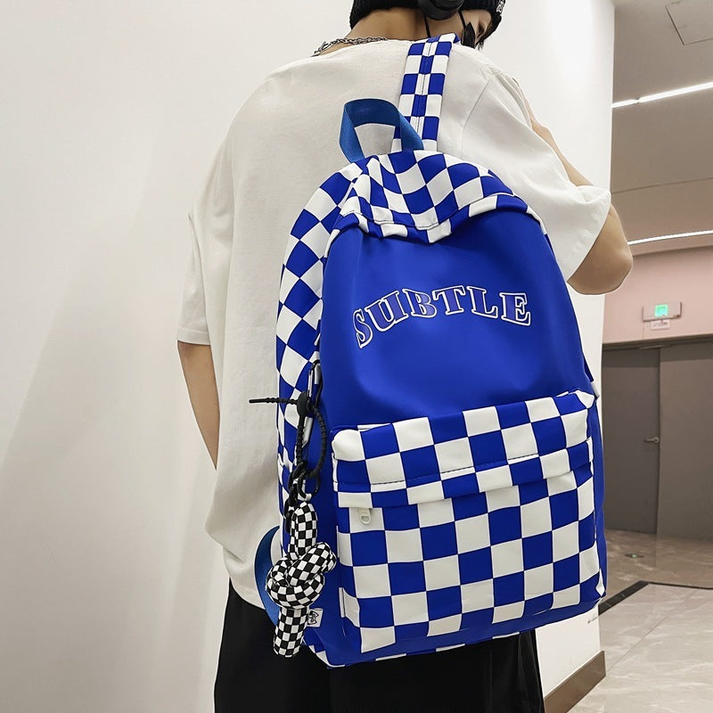 Person wearing a blue and white checkered backpack with 'SUBTLE' text.