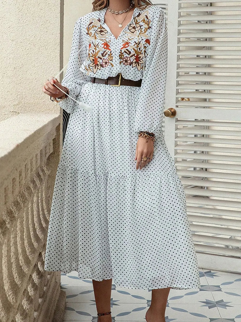 Woman wearing a white midi dress with black polka dots and floral embroidery. 