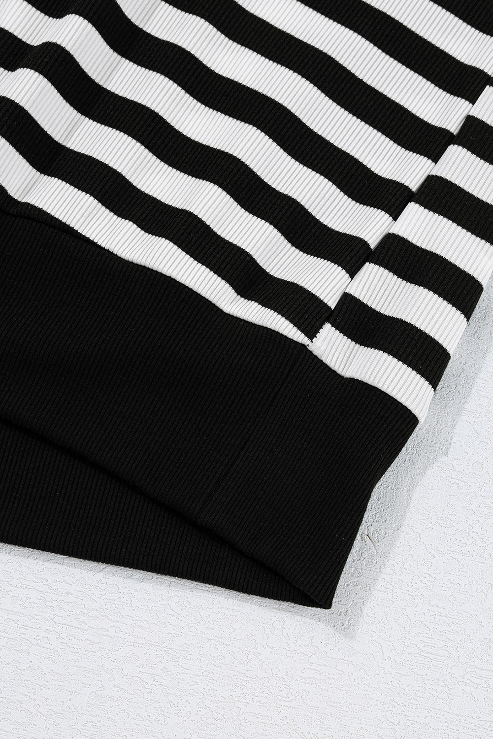 Close-up of black and white striped fabric on a textured white surface