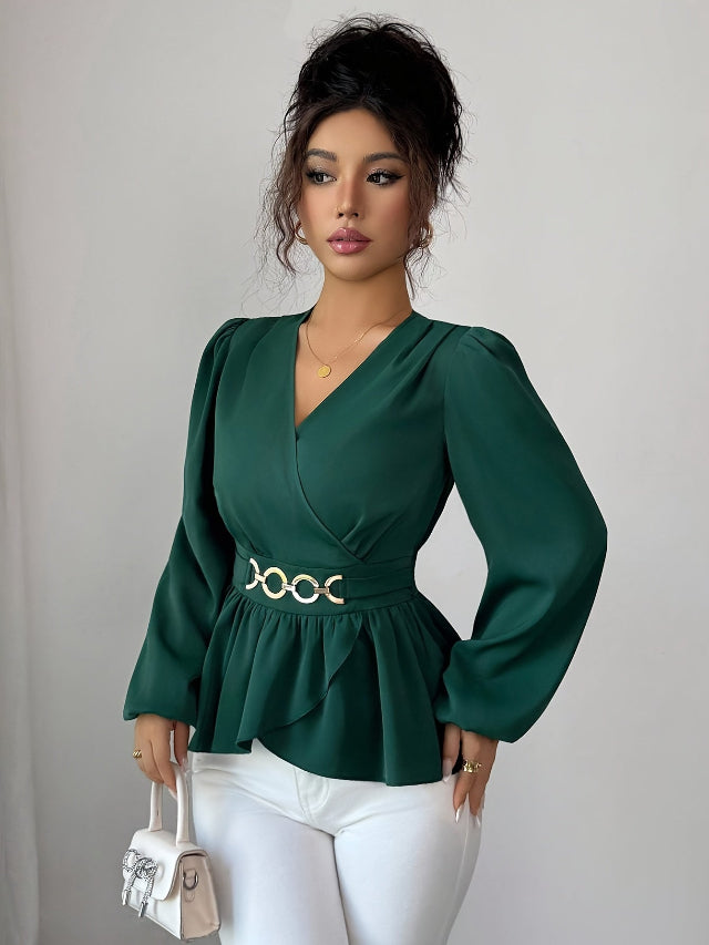 Woman wearing a green peplum top with a belt and white pants against a plain background