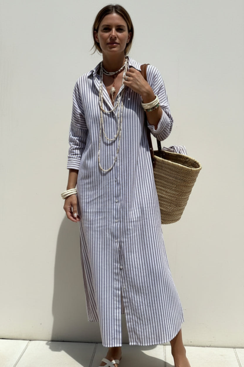 Person wearing a striped dress holding a woven bag against a light background