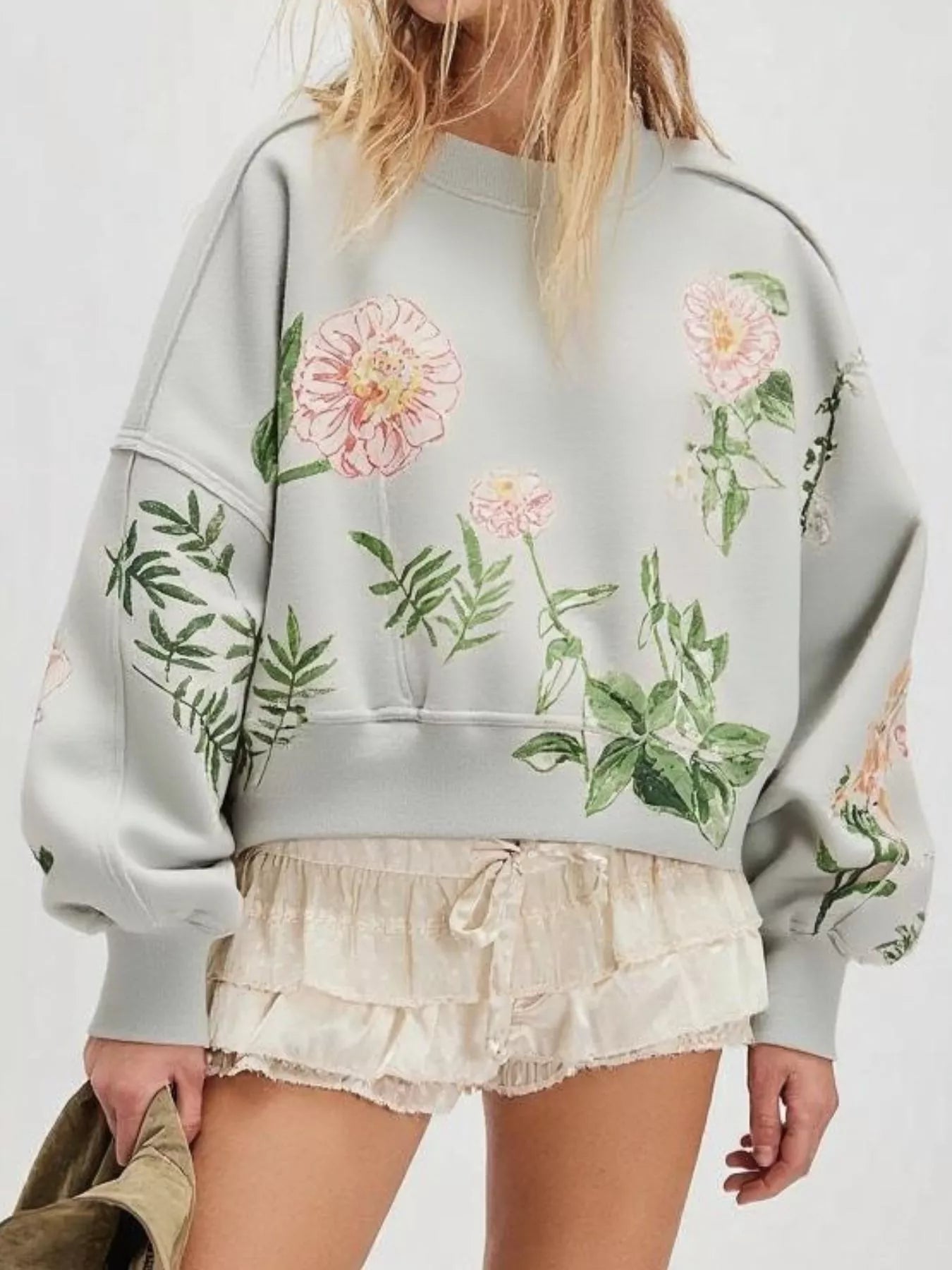 Person wearing a light blue sweatshirt with floral designs 